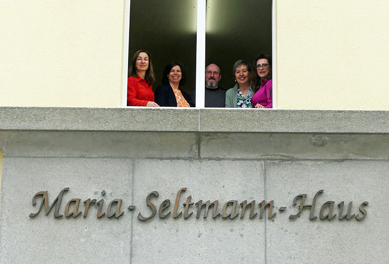 Das Bild Zeigt 5 Personen an einem Fenster. Darunter ist der Schriftzug Maria-Seltmann-Haus zu sehen.